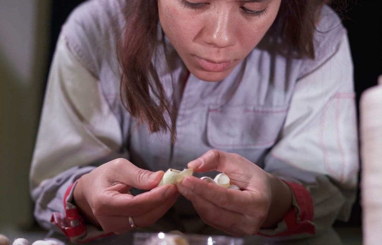 Film still showing woman looking at something in her hands. Image: Aslı Hatipoğlu and Alyssa Gersony,
