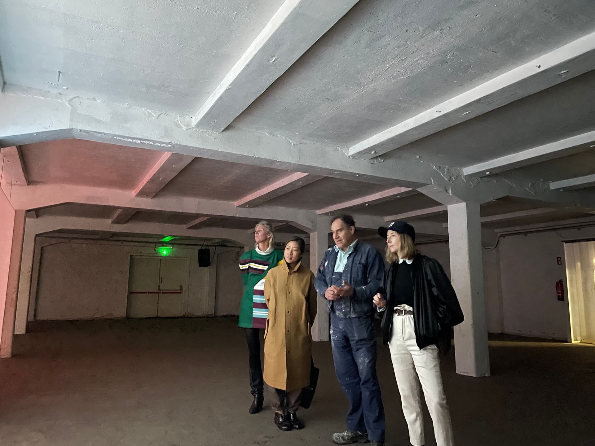 Four people on a guided tour in a basement with a white ceiling