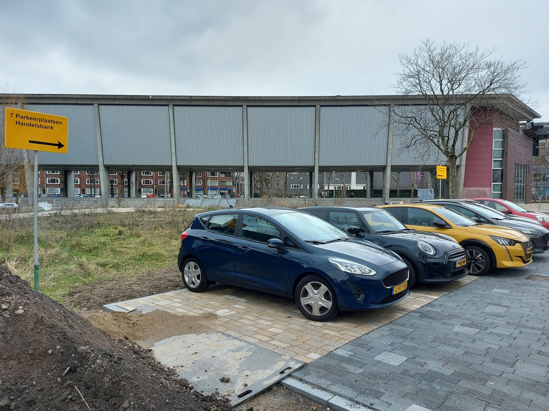 Cars on a parking lot in front of Het Nieuwe Instituut against a grey sky.