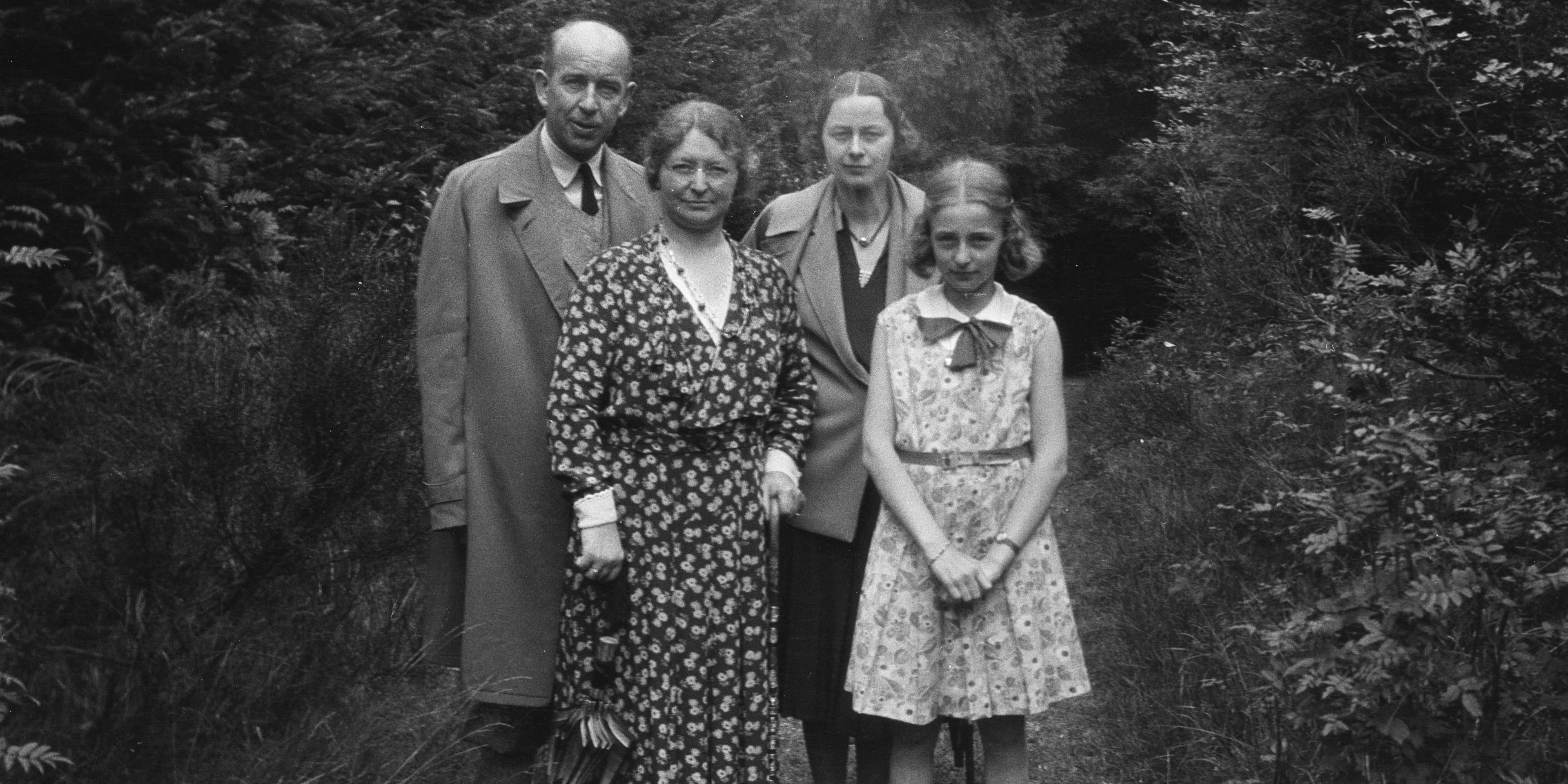 Een zwart-witfoto van de familie Sonneveld, poserend buiten in een bosrijke omgeving.