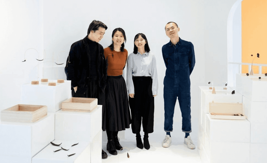 Two men and two women are standing in the middle of a white room surrounded by sculptures.