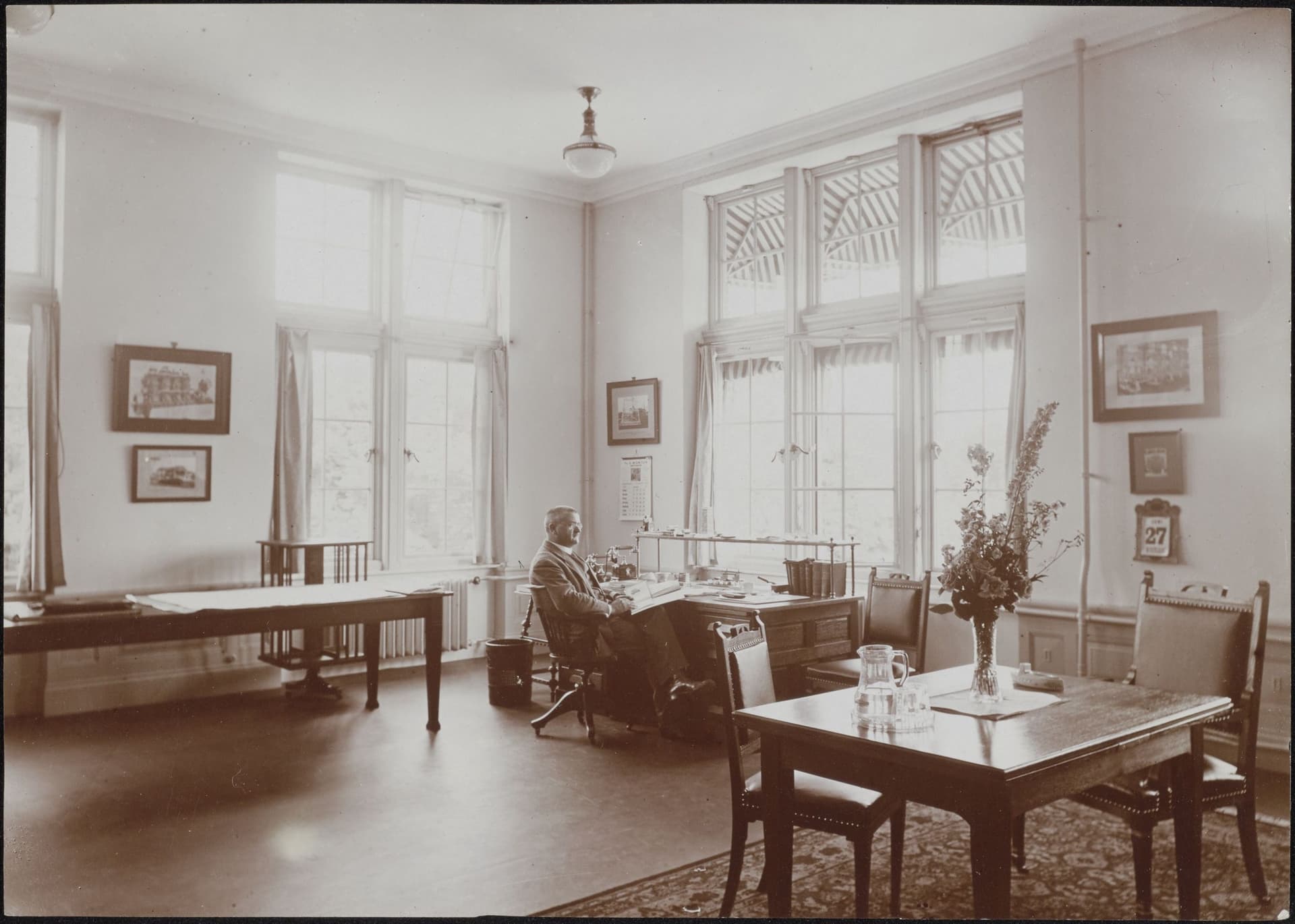 Kantoren worden vandaag de dag zo efficient mogelijk  ingericht, maar dat was in het begin van de jaren 1900 nog heel anders. Alleen de enorme ruimte al. Het lijkt meer op een woonkamer, met die fraaie vitrages en kleden, en kunst aan de muur.… 