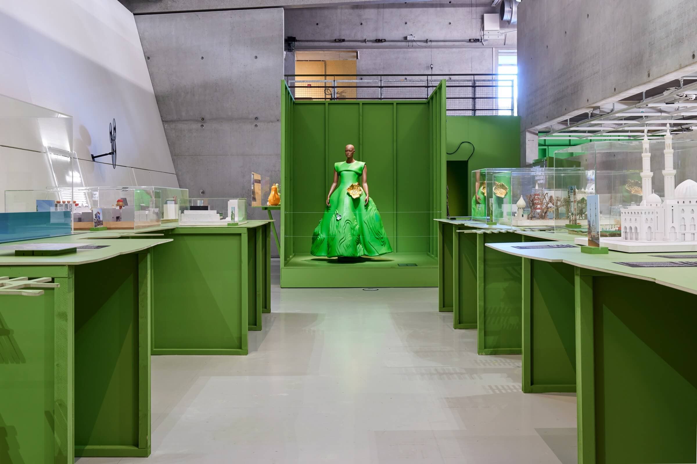 Zaaloverzicht in de tentoonstelling De architectuur van een wondere wereld, Het Nieuwe Instituut 2021-2022, met centraal in beeld Marga Weimans, Green Landscape Dress (uit de collectie Wonderland, spring/summer 2009), 2008, polyurethaan, kunsts… 