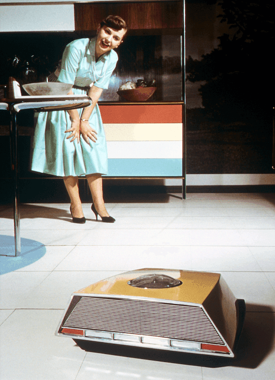 A "demonstration lady" takes delight in the work of a robotic floor cleaner in the "Miracle Kitchen" at the 1959 American National Exhibition in Moscow.
US Library of Congress, Prints and Photographs Division, Look collection. 