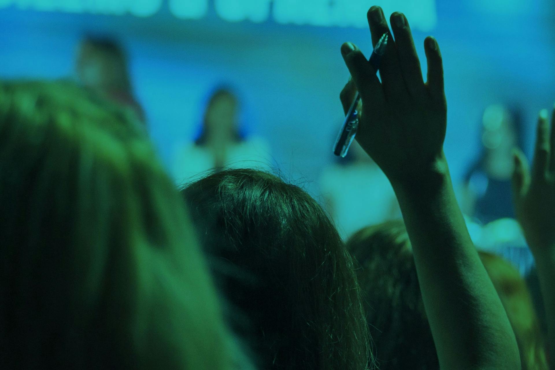 Close up of a girl with a raised hand. The image has a blue undertone