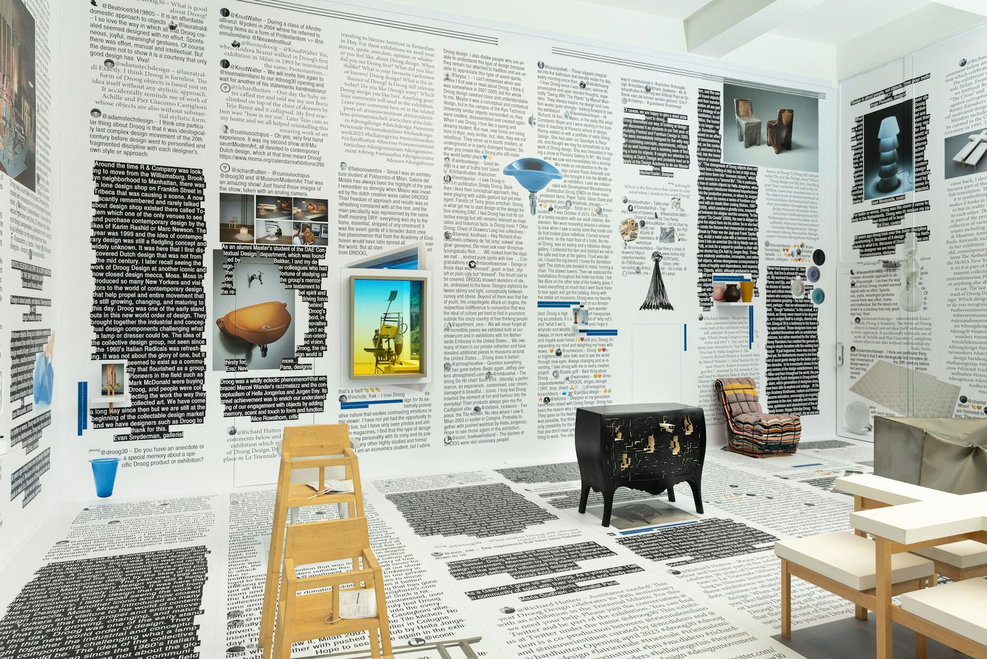 Foto van een tentoonstellingsruimte met daarin diverse meubels en designobjecten in onconventionele vormen en materialen. Op de muren en de vloer zijn teksten in uiteenlopende lettertypes en kleuren.