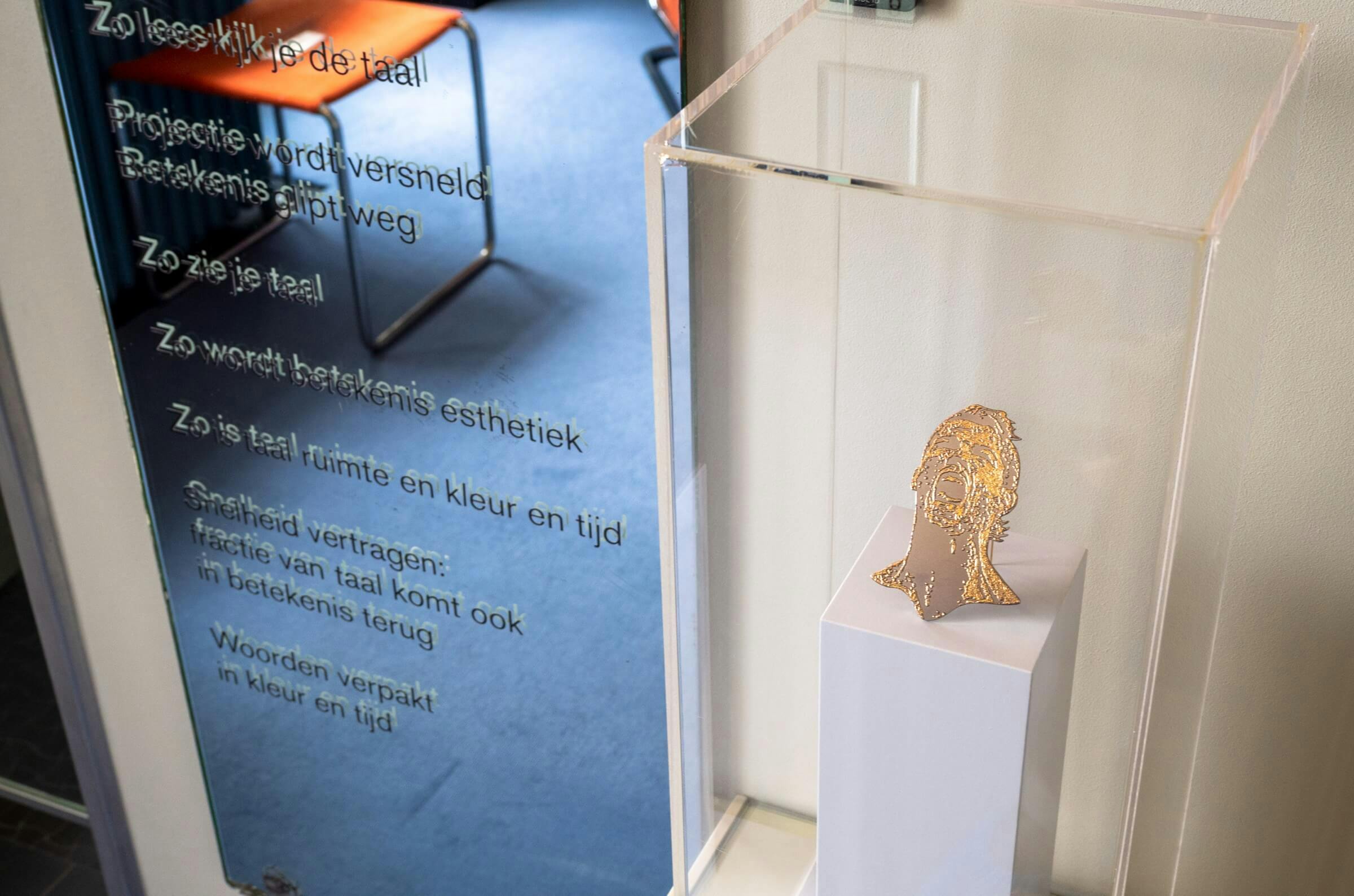 Impressie van de tentoonstelling Gijs Bakker & K. Schippers: Beginselen in Huis Sonneveld, 11.07.2020 – 10.01.2021. Foto: Johannes Schwartz. Op deze foto staan het sieraad ‘Ronaldo, Gold under Titanium (377)’ van Gijs Bakker en het gedicht ‘Emb… 